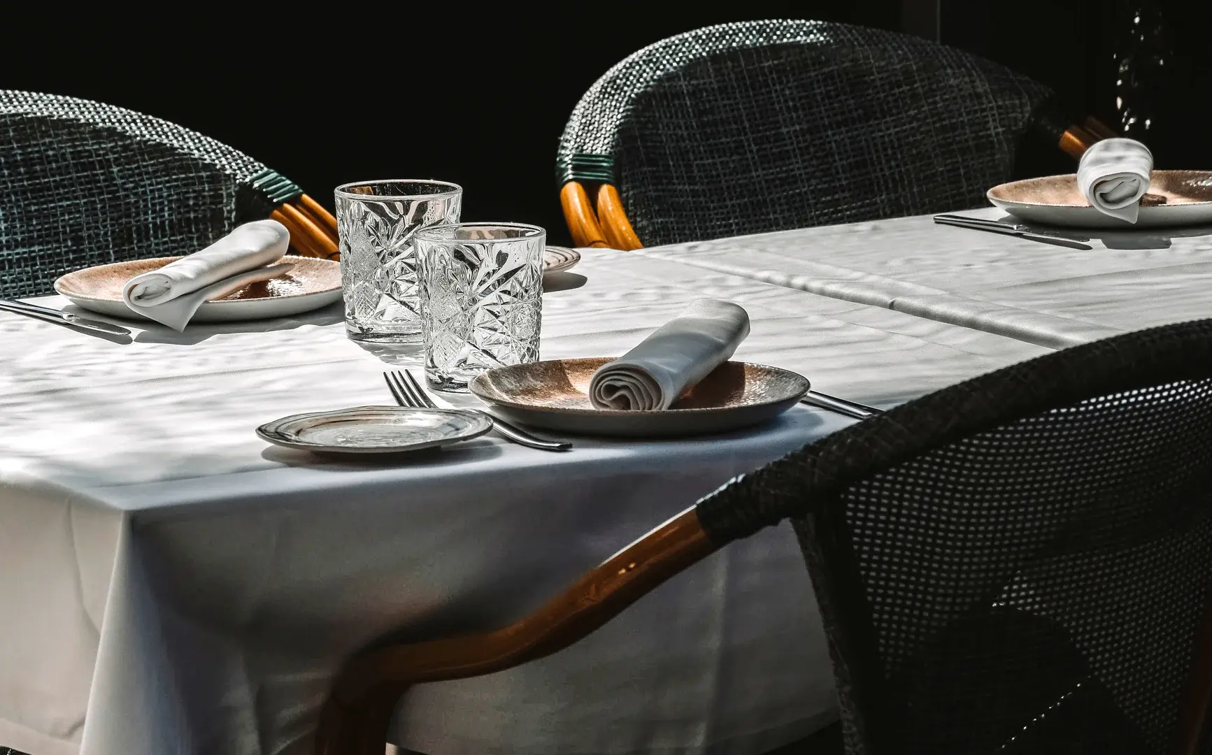 Glasses and plates on a restaurant table set for three on a white tablecloth