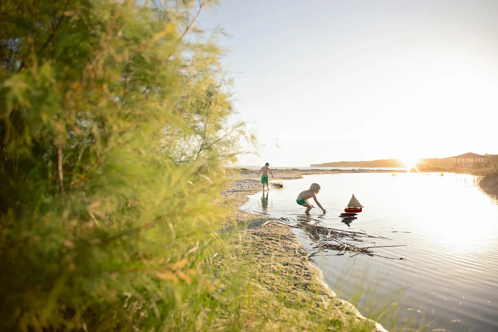 Two Boys Playing in Water with Toy Boat