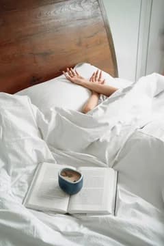 Woman Relating in Bed with Book and Coffee