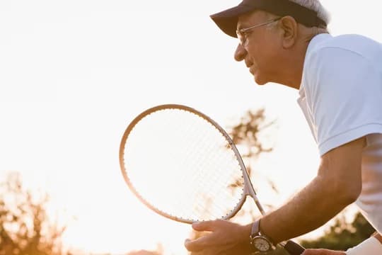 Older Man Playing Tennis Sunlit Background