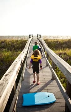 157481 Kids Walking on Boardwalk Towards Beach with Boogie Boards USP Crop